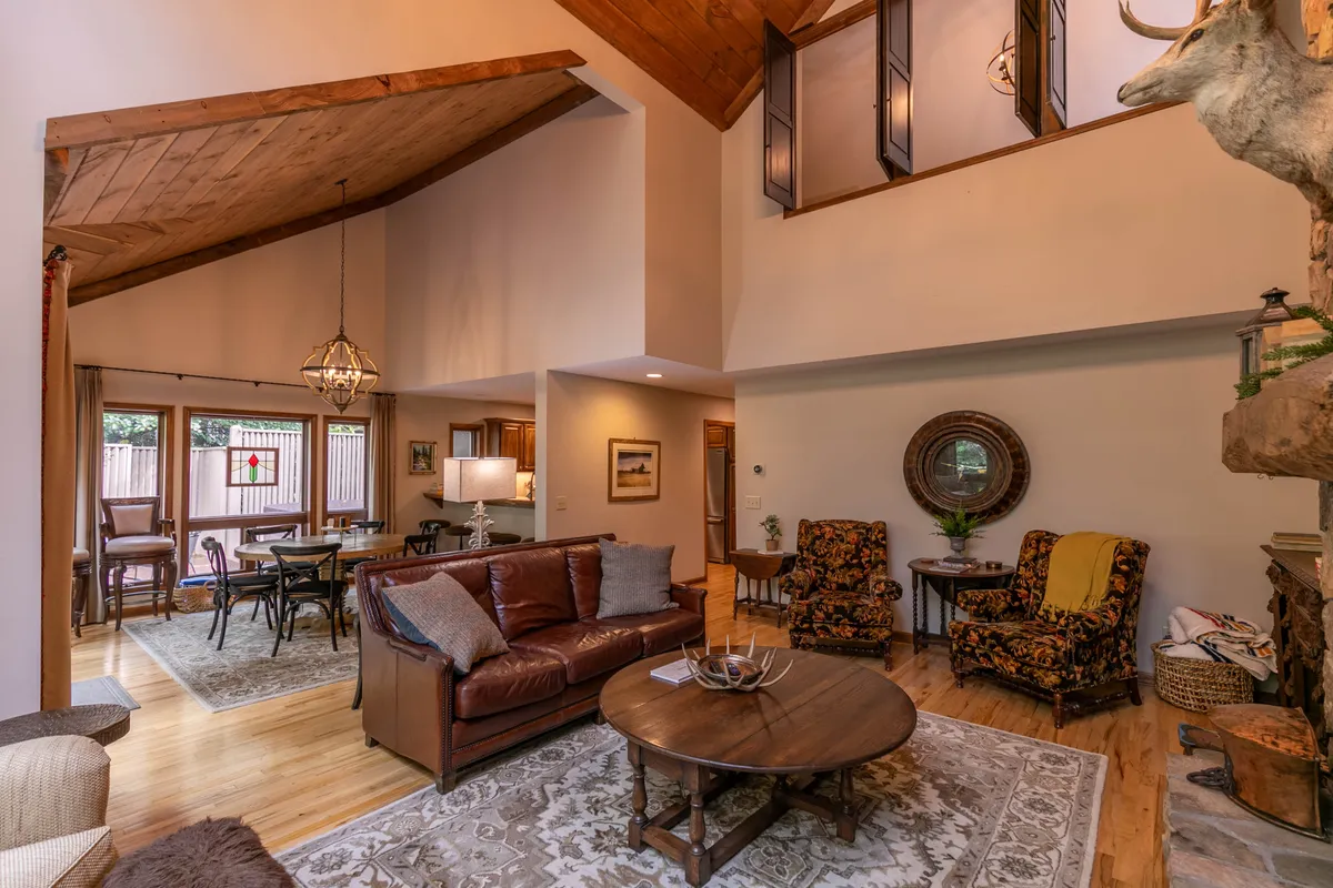 This interior scene features a spacious living area anchored by a plush leather sofa, wooden coffee table, and decorative chairs arranged around a cozy fireplace. The ambiance exudes comfort and warmth, ideal for group gatherings or relaxing evenings.