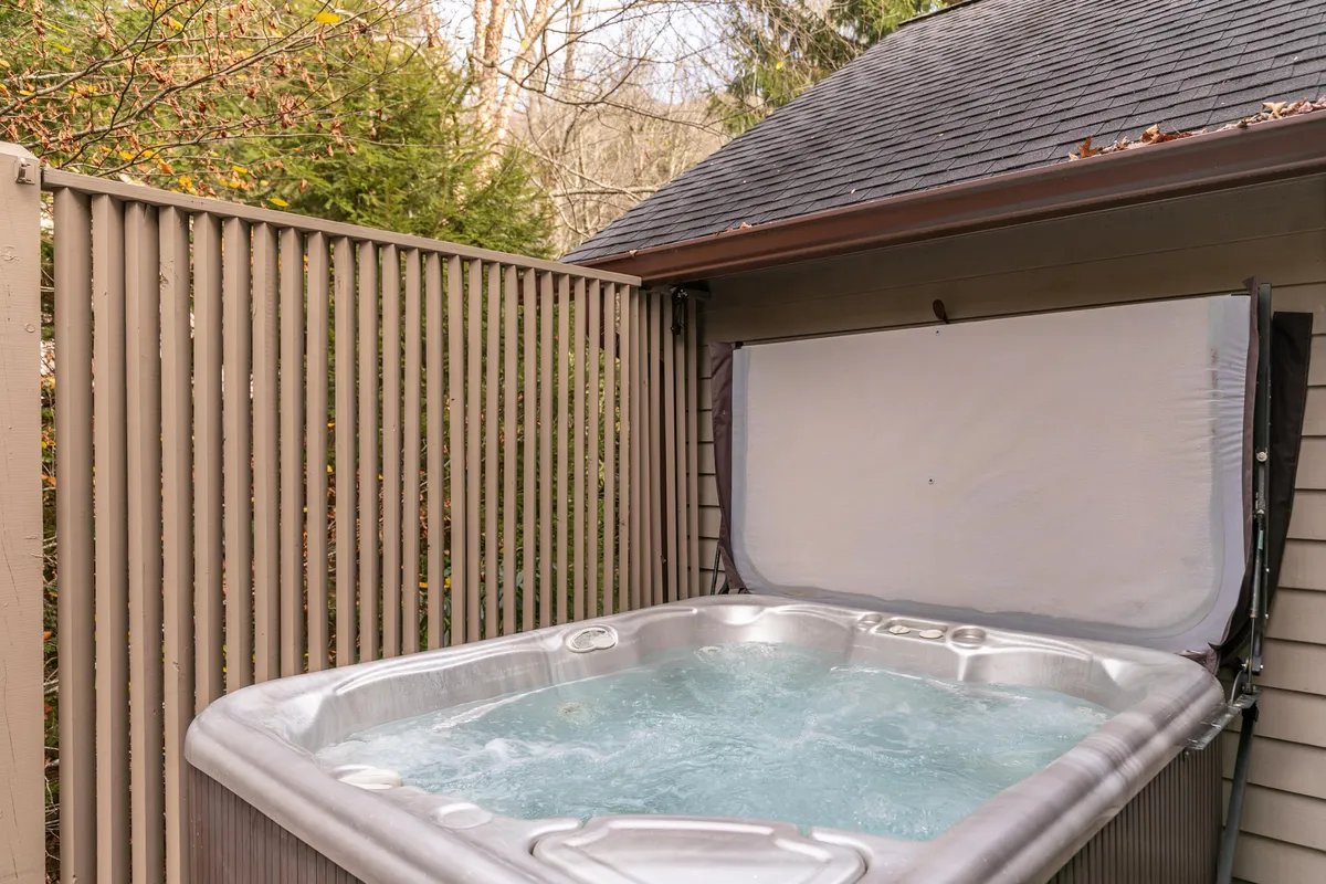 This image showcases an inviting outdoor hot tub nestled among lush greenery, with a wooden fence providing privacy. The serene setting is perfect for relaxation and soaking in nature, aligning with the section's focus on wellness and scenic lounging.