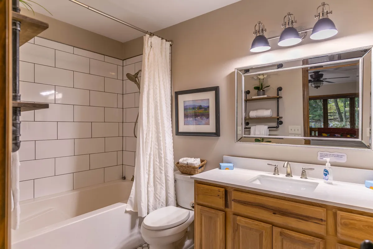 A spa-inspired bathroom showcasing a deep soaking bathtub, a wide sink with a sleek mirror, and neatly arranged towels on open shelves. Natural light and minimalist decor create a refreshing, upscale atmosphere.
