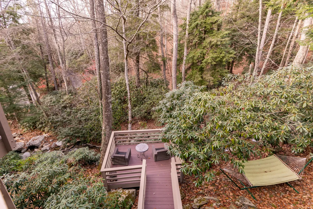 A wooden deck offers a comfortable seating area and a peaceful hammock, embraced by tall trees and a natural landscape. The setting is ideal for morning yoga, quiet reading, or simply enjoying the fresh air.